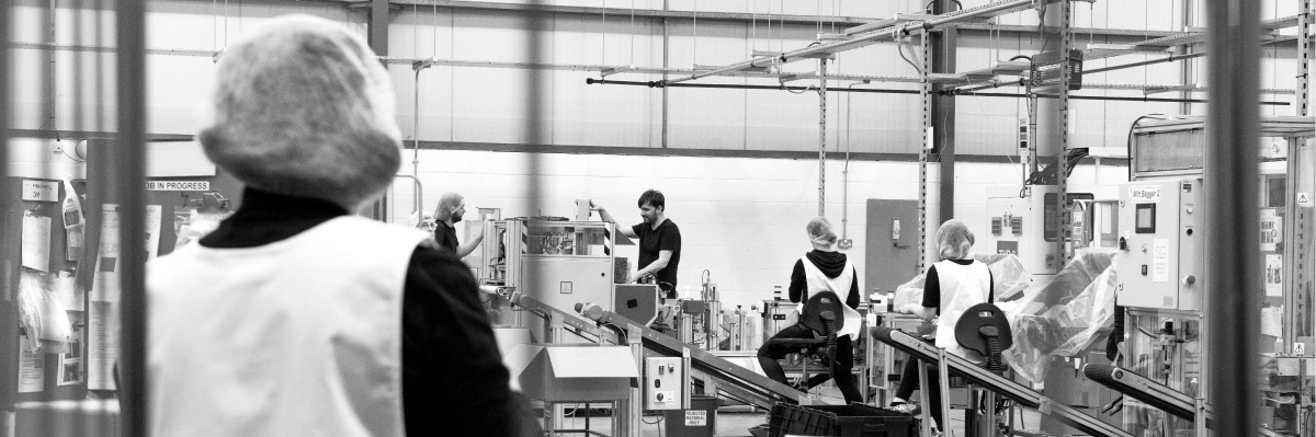 image: a black and white photo of inside our factory with people working