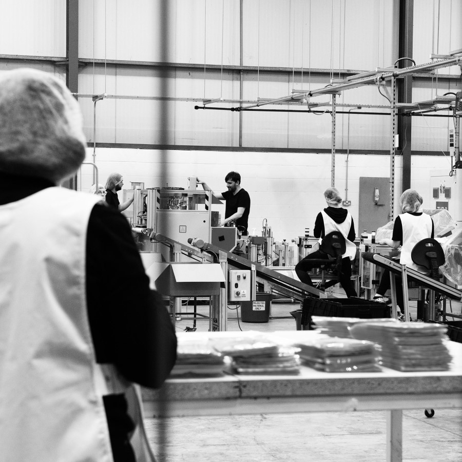 image: a black and white photo of inside our factory with people working